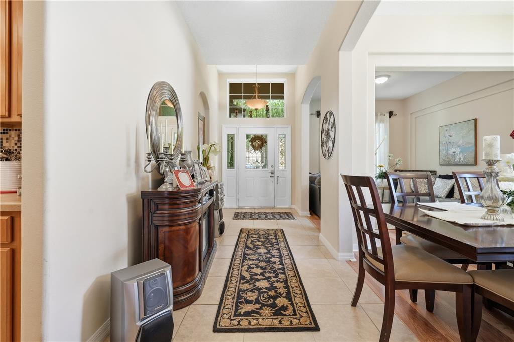 A bright entryway features tile flooring, a dark wood console table, and a front door — 458 WOODFORD DRIVE, DEBARY, FL