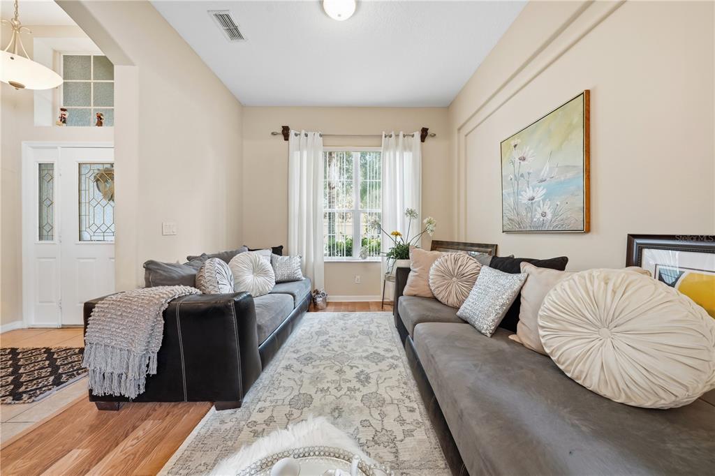 A living room features two gray sofas facing each other on a patterned area rug — 458 WOODFORD DRIVE, DEBARY, FL