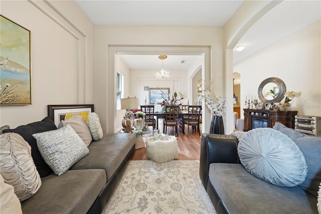 A living room with gray sofas leads into a dining area with a chandelier — 458 WOODFORD DRIVE, DEBARY, FL
