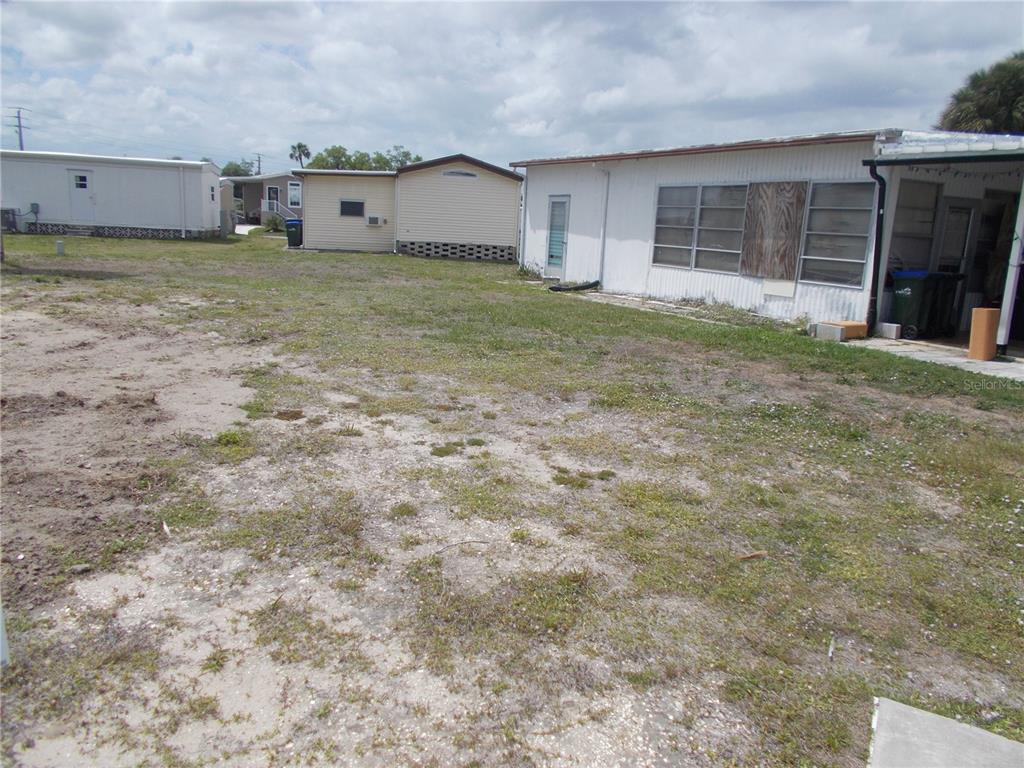 A view of a sandy, grassy yard between several mobile homes — 6759 NEIGHBORLY COURT, NORTH PORT, FL
