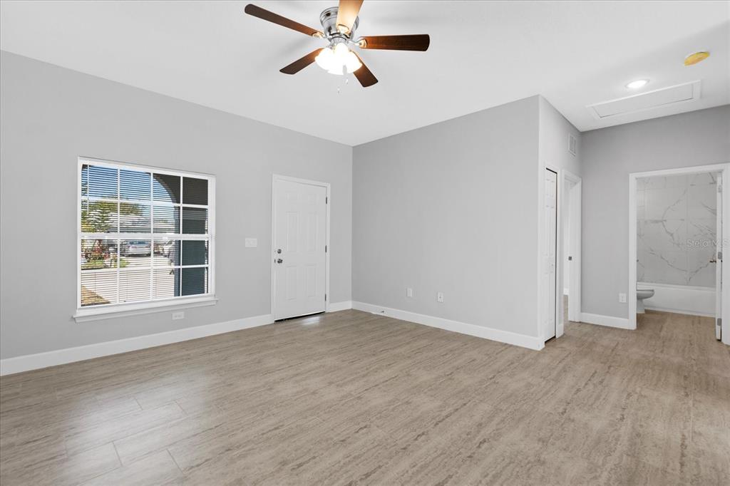 A bedroom with light gray walls, wood-look tile flooring, a ceiling fan, and an attached bathroom — 13 TROUT WAY UNIT A & B, KISSIMMEE, FL