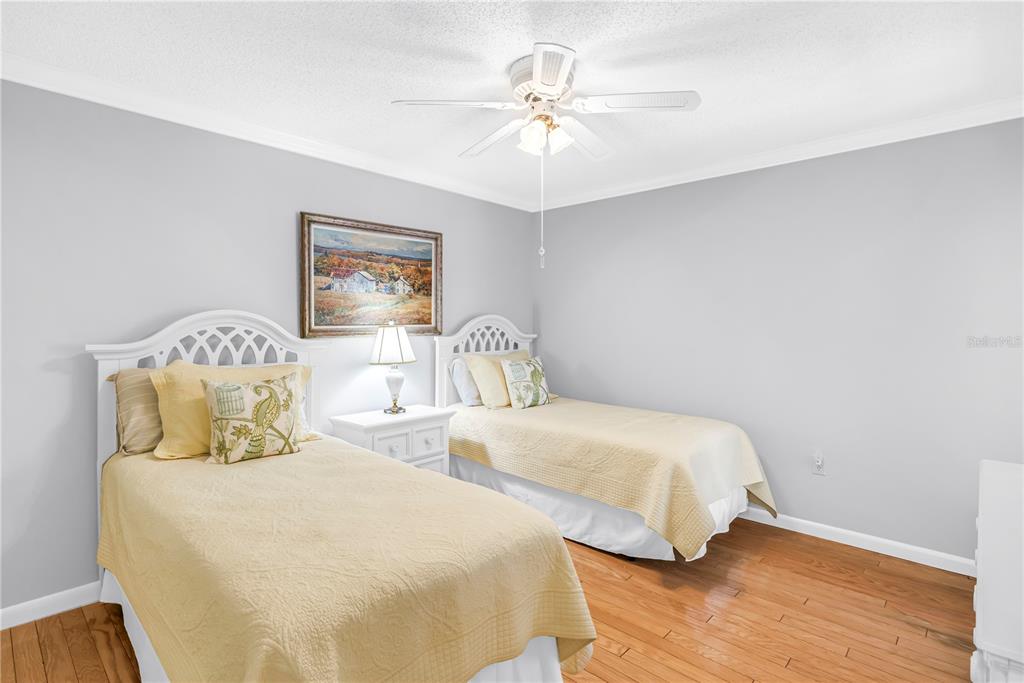 A bedroom features two twin beds with yellow bedding, a shared nightstand, and hardwood floors — 3174 WINDRUSH UNIT 25, SARASOTA, FL