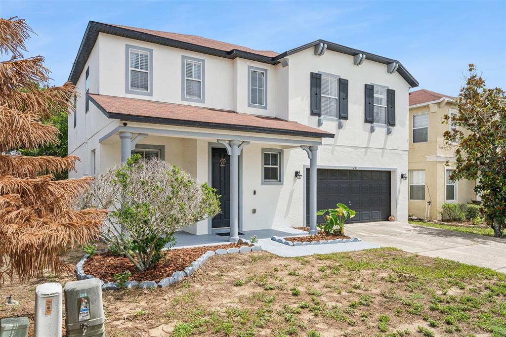 A two-story house with a covered front porch, a garage, and a small front yard — 233 ROSSELLI BOULEVARD, DAVENPORT, FL