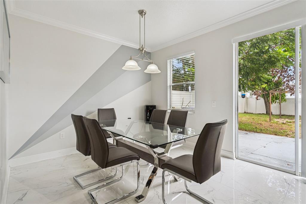 A dining room with a glass table, gray chairs, and a diagonal painted wall accent — 233 ROSSELLI BOULEVARD, DAVENPORT, FL