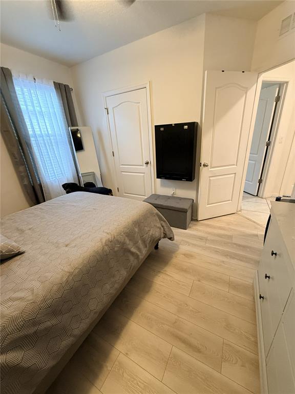 A bedroom features a bed, light wood-look flooring, two white doors, and a wall-mounted desk — 329 WINGED ELM DRIVE, DEBARY, FL