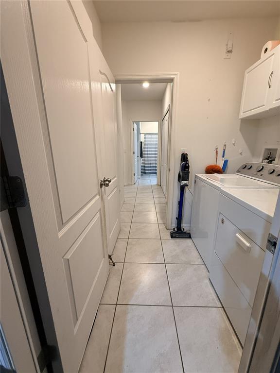 A laundry room with white tile floors, a washer, a dryer, and a hallway beyond — 329 WINGED ELM DRIVE, DEBARY, FL