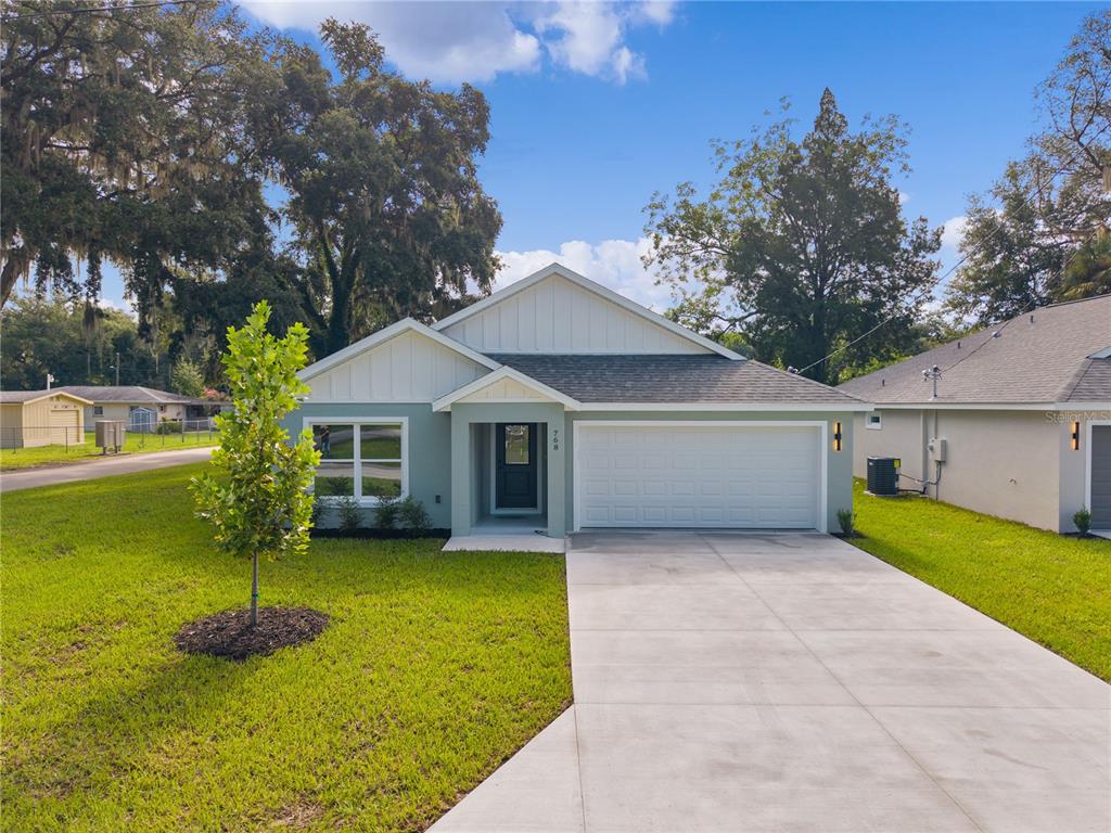 A single-story house with a light green exterior, white trim, and a two-car garage — 768 POWELL STREET, WILDWOOD, FL