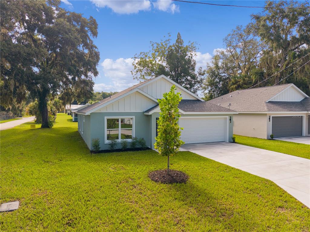 A single-story house with light green siding, a white garage, and a concrete driveway — 768 POWELL STREET, WILDWOOD, FL