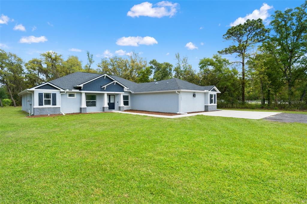 A single-story house with gray siding, blue accents, and a large front lawn — 11099 YELLOW HAMMER ROAD, WEEKI WACHEE, FL