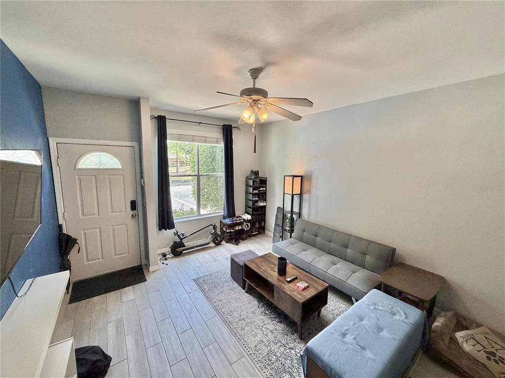 A living room features light wood-look tile flooring, a gray sofa, and a ceiling fan — 3575 SW 30TH WAY UNIT 121, GAINESVILLE, FL