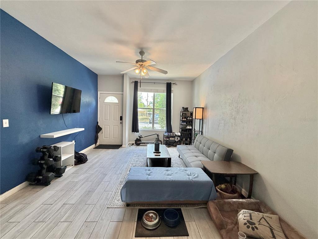 A living room features a blue accent wall, gray tile flooring, and a gray sofa — 3575 SW 30TH WAY UNIT 121, GAINESVILLE, FL