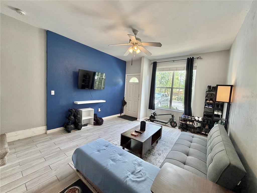 A living room features a blue accent wall, gray tile flooring, and a gray sofa — 3575 SW 30TH WAY UNIT 121, GAINESVILLE, FL