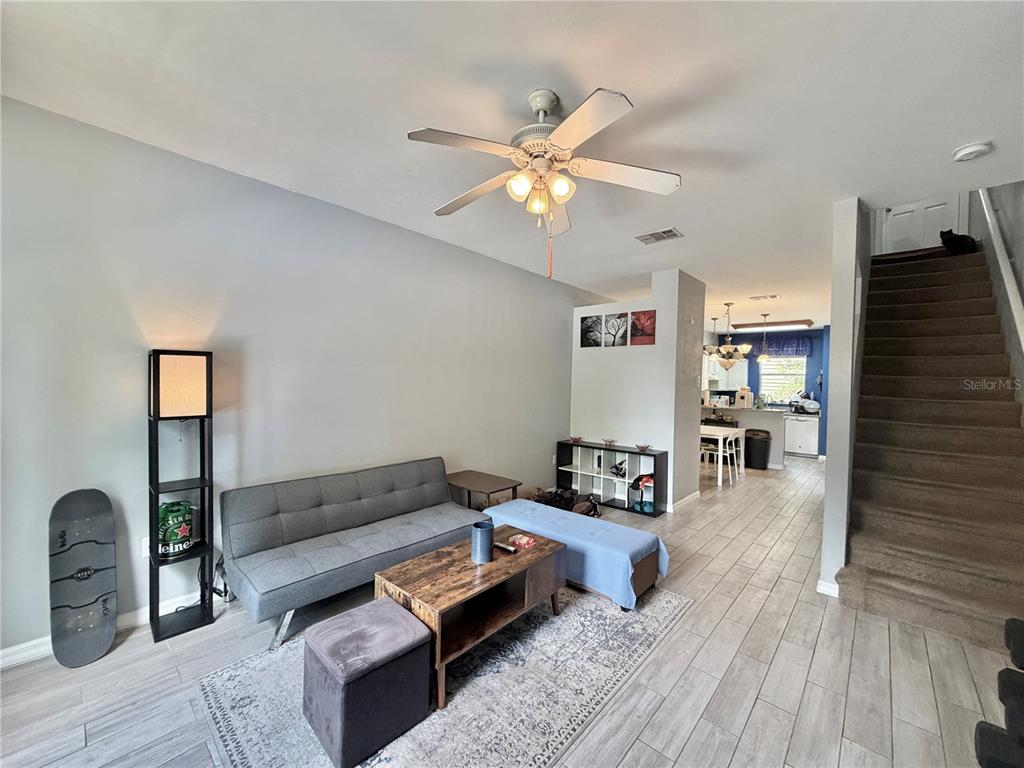 A living room with gray flooring, a sofa, a coffee table, and stairs leading upward — 3575 SW 30TH WAY UNIT 121, GAINESVILLE, FL