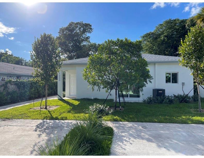 A white single-story house features a concrete driveway, green lawn, and several trees — 213 NW 12th St, Pompano Beach FL 33060, POMPANO BEACH, FL