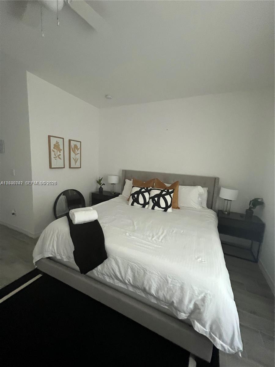 A bedroom features a gray upholstered bed, white bedding, and two framed wall art pieces — 213 NW 12th St, Pompano Beach FL 33060, POMPANO BEACH, FL