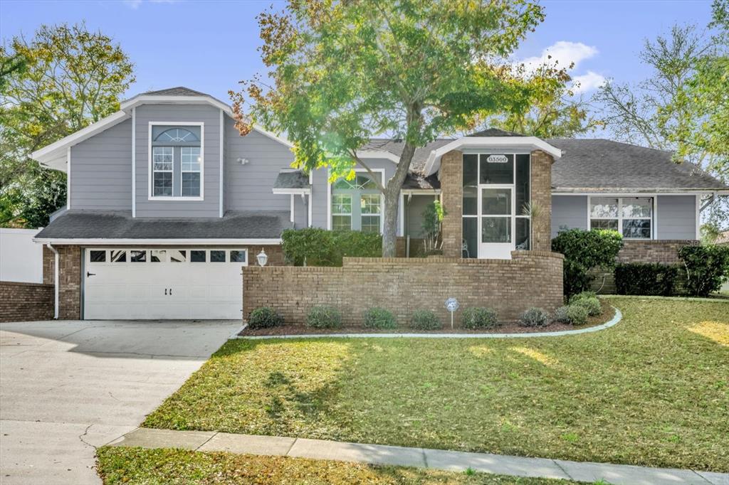 A two-story house with gray siding, a brick facade, a two-car garage, and a front lawn — 3500 SAIL FISH AVENUE, FRUITLAND PARK, FL
