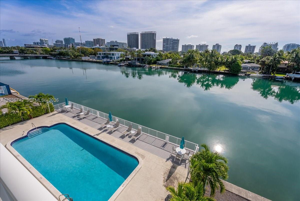 An elevated view of a swimming pool deck overlooking a canal and city skyline — 9381 E Bay Harbor Dr # 404S, Bay Harbor Islands FL 33154, BAY HARBOR ISLANDS, FL