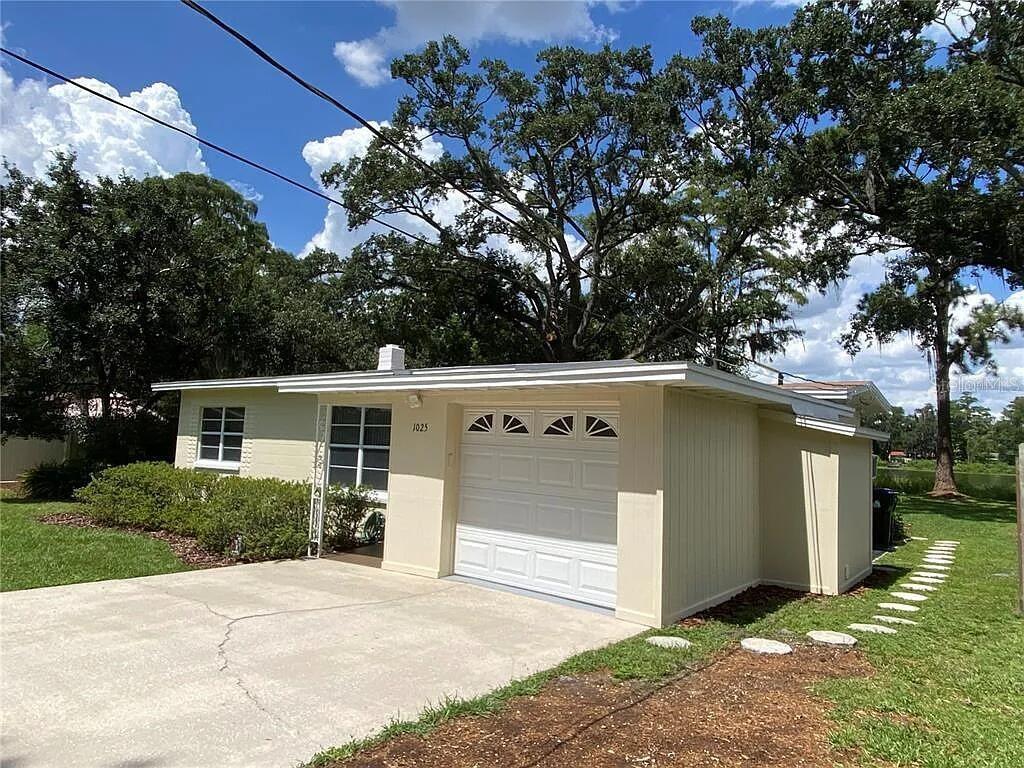 A single-story house with a light-colored exterior, a one-car garage, and large shade trees — 1025 LAKE JESSAMINE DRIVE, ORLANDO, FL