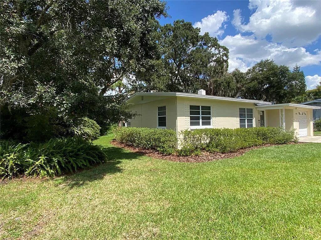 A light yellow, single-story house with a flat roof sits on a grassy lot — 1025 LAKE JESSAMINE DRIVE, ORLANDO, FL