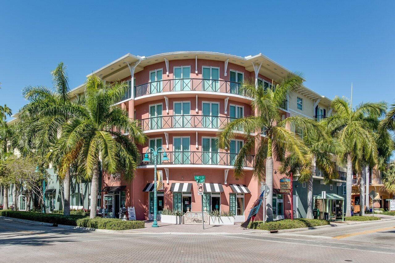 A three-story pink building with curved balconies and ground-floor storefronts sits on a corner lot — 235 NE 1st Street # 504, Delray Beach FL 33444, DELRAY BEACH, FL