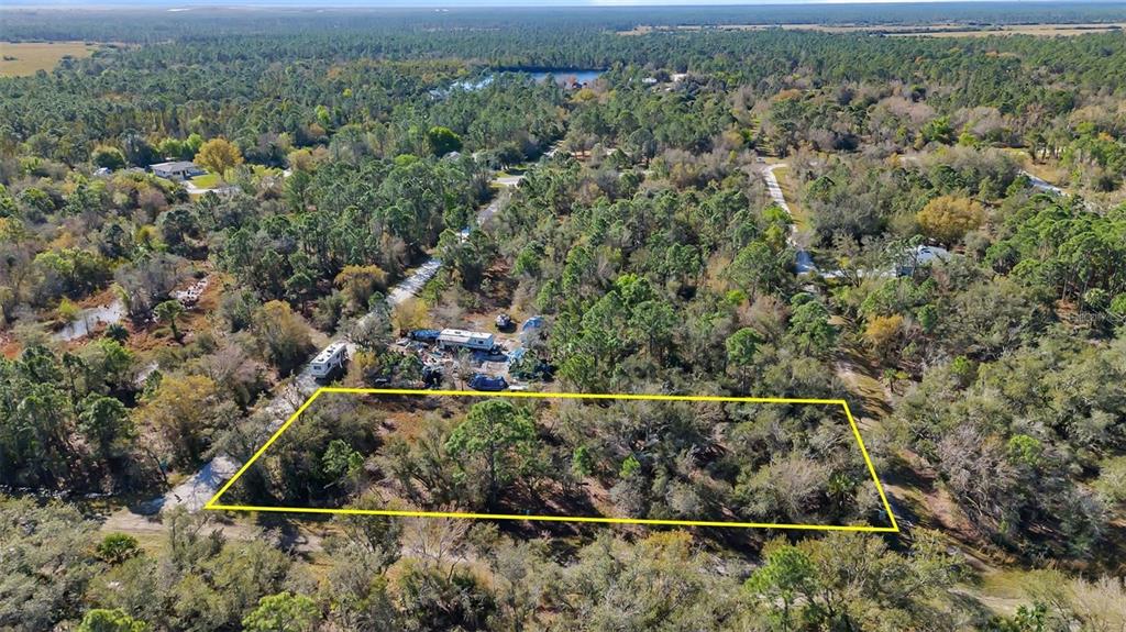 An aerial view shows a rectangular plot of land outlined in yellow amidst wooded terrain — 13142 BANYAN DRIVE, PUNTA GORDA, FL