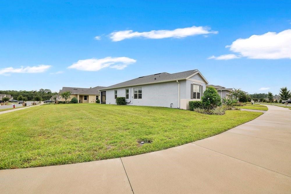 A side view of a light-colored suburban house with a large lawn and sidewalk — 17718 BLAZING STAR CIRCLE, CLERMONT, FL