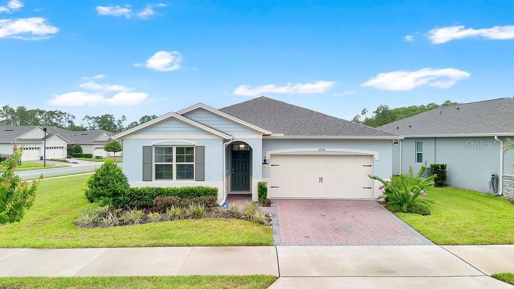 A single-story house with light blue siding, a brick driveway, and a two-car garage — 17718 BLAZING STAR CIRCLE, CLERMONT, FL