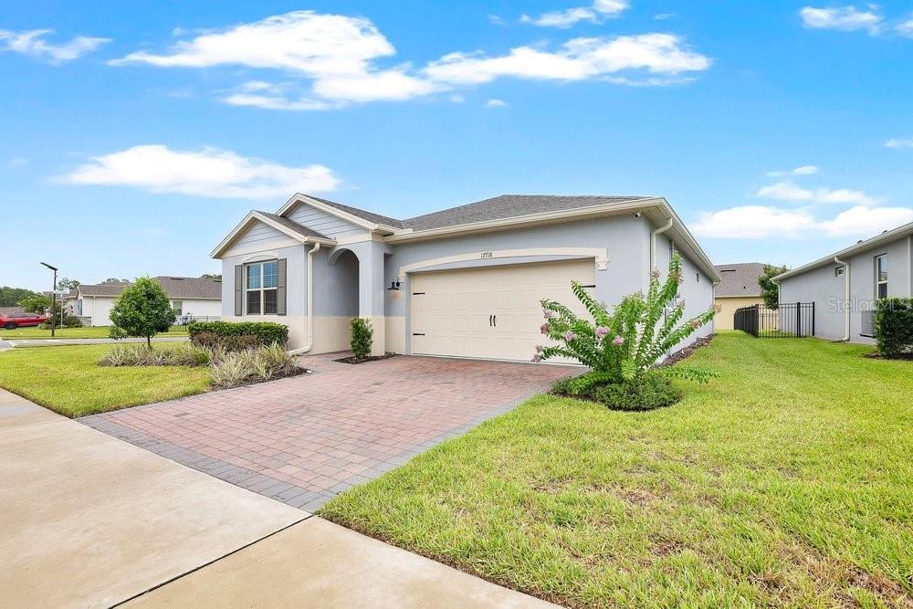A single-story house with a light gray exterior, a two-car garage, and a paved driveway — 17718 BLAZING STAR CIRCLE, CLERMONT, FL