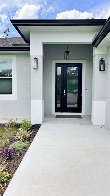 The exterior of a modern house features a black front door and matching wall lanterns — 3399 LA GOY STREET, NORTH PORT, FL