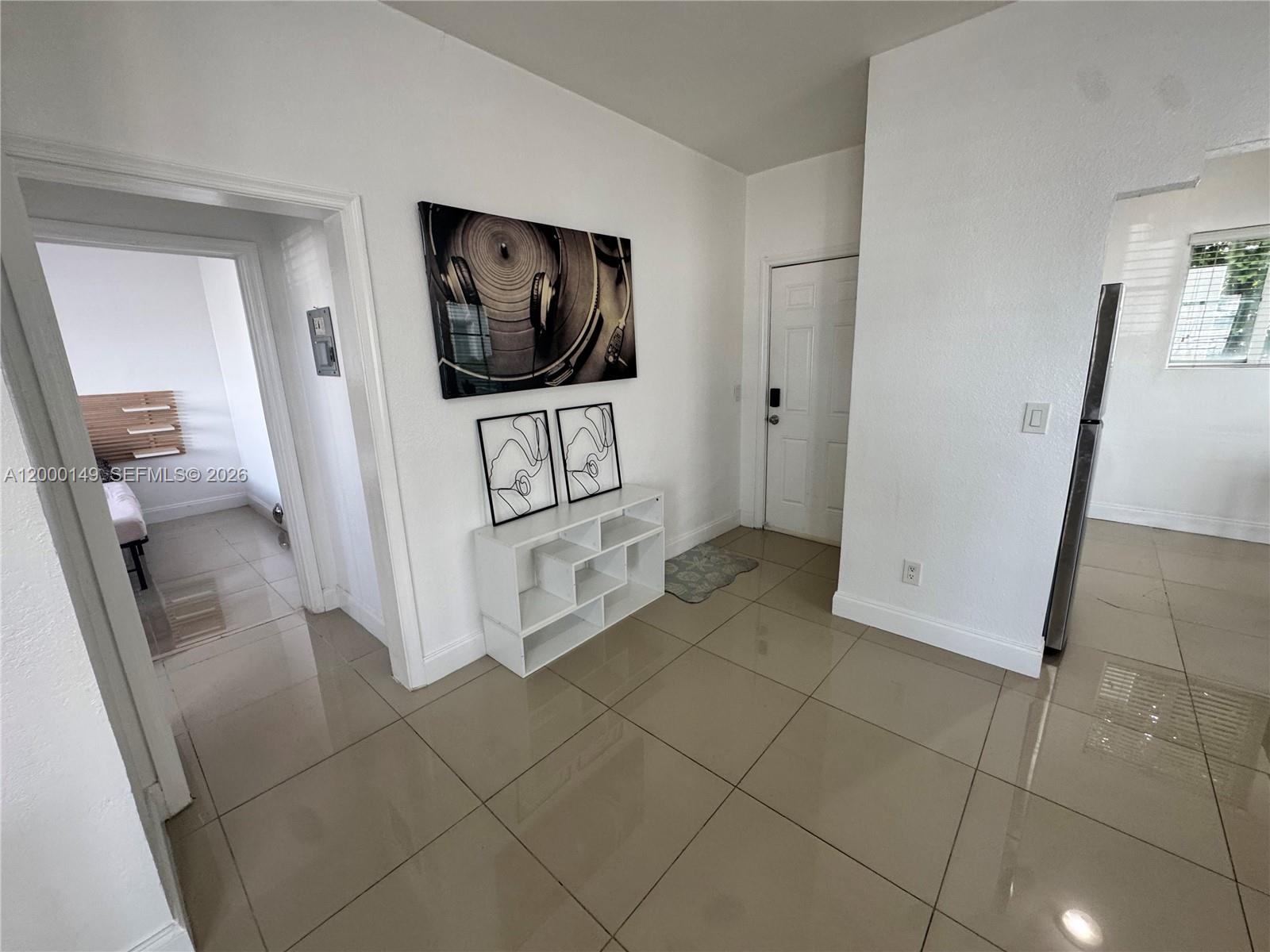 A tiled entryway features a white storage unit, wall art, and a doorway to a bedroom — 8415 Harding Ave # 9, Miami Beach FL 33141, MIAMI BEACH, FL