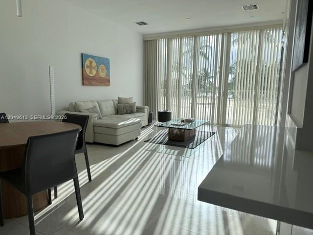 A modern living room features a white sectional sofa, glass coffee table, and floor-to-ceiling blinds — 881 Ocean Dr # L2, Key Biscayne FL 33149, KEY BISCAYNE, FL