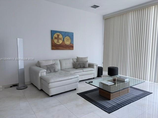 A living room features a white sectional sofa, a glass coffee table, and vertical blinds — 881 Ocean Dr # L2, Key Biscayne FL 33149, KEY BISCAYNE, FL