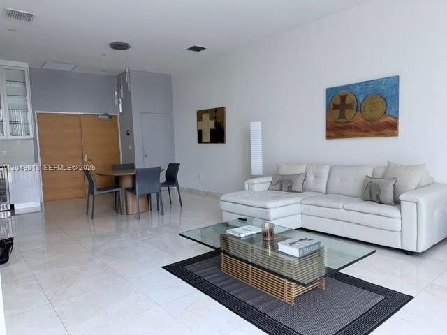 A modern living room features a white sectional sofa, glass coffee table, and dining area — 881 Ocean Dr # L2, Key Biscayne FL 33149, KEY BISCAYNE, FL