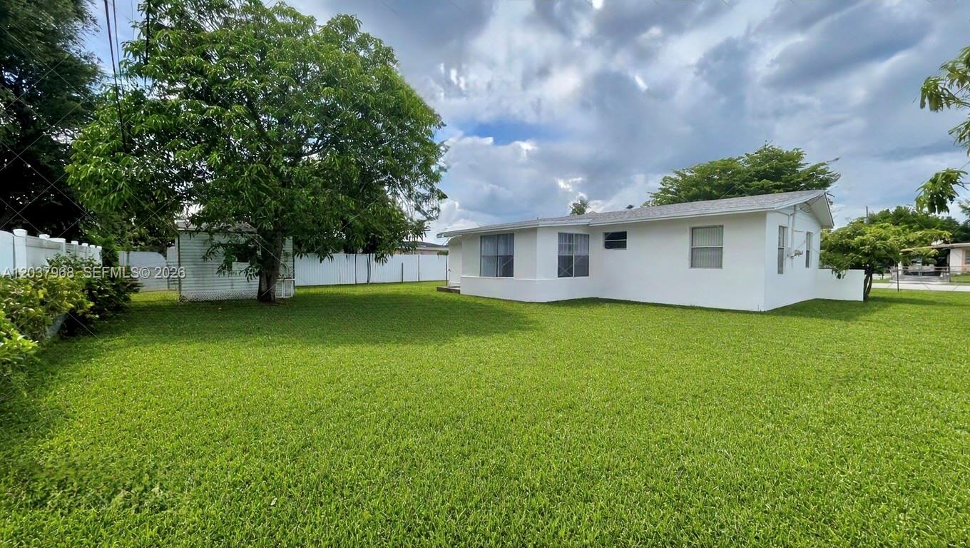 A white single-story house with a large grassy backyard and a small shed — 3460 NW 5th Ct, Lauderhill FL 33311, LAUDERHILL, FL