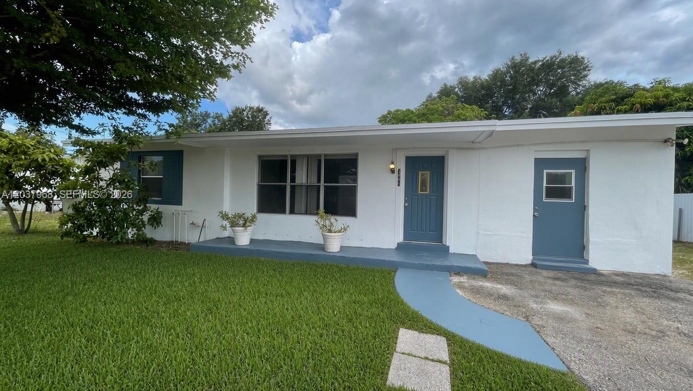A white single-story house features a blue front door, a side door, and a porch — 3460 NW 5th Ct, Lauderhill FL 33311, LAUDERHILL, FL