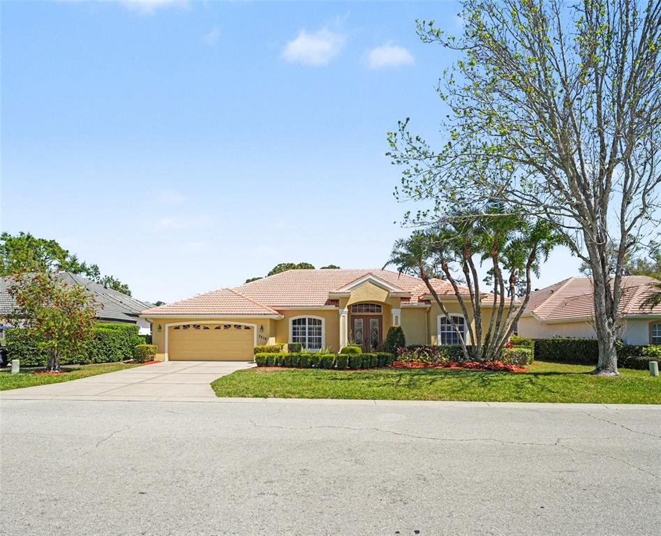 A single-story house with a tan stucco exterior, a tile roof, and a two-car garage — 7219 COACHLIGHT STREET, SARASOTA, FL