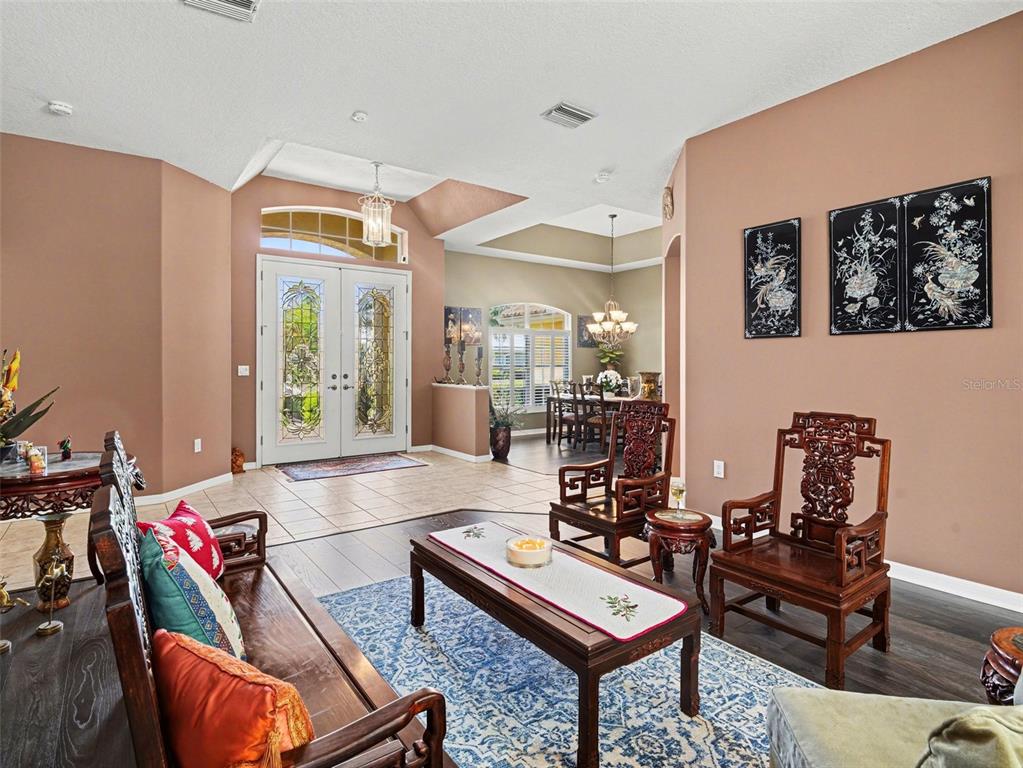 A living room features dark wood furniture, a blue patterned rug, and a tiled entryway — 7219 COACHLIGHT STREET, SARASOTA, FL