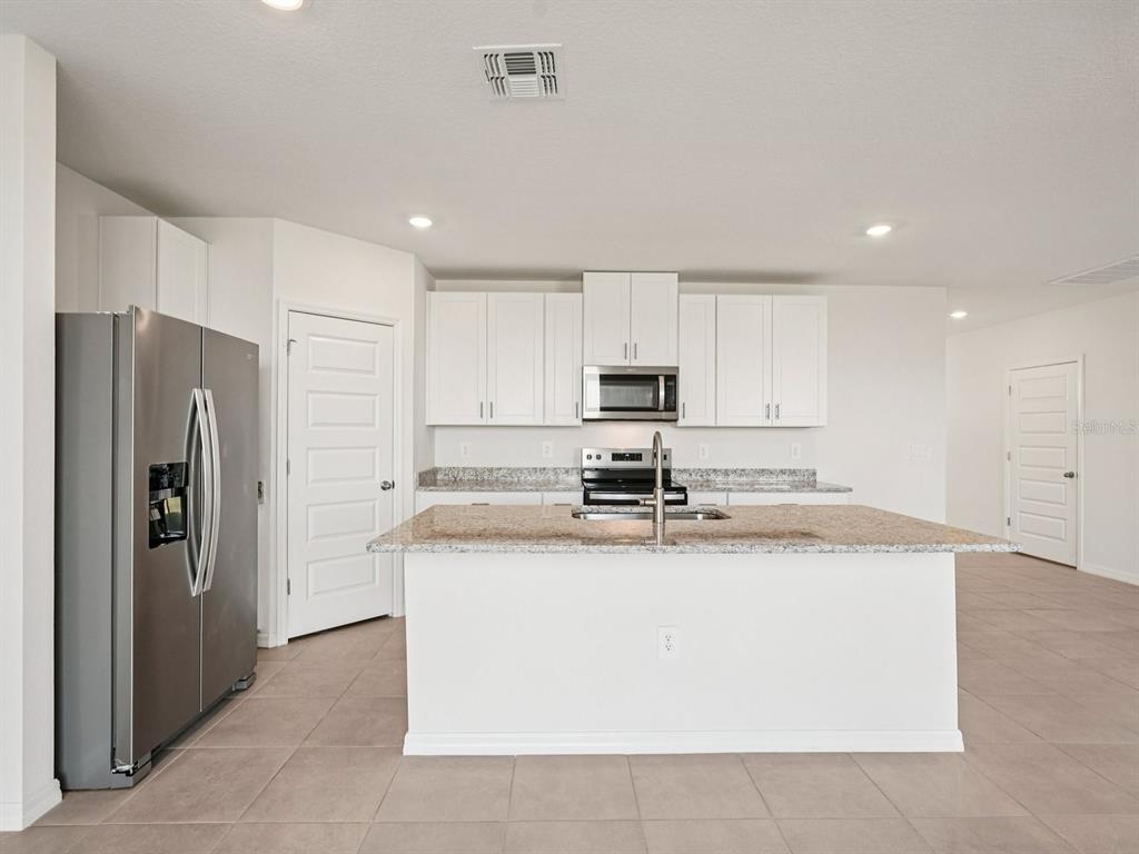 A kitchen with white cabinets, granite countertops, a center island, and stainless steel appliances — 13613 SHELLMORE AVENUE, PALMETTO, FL