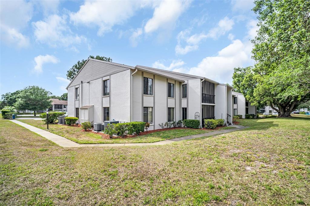 A two-story apartment building with beige siding and a sidewalk on a grassy lot — 2642 PINE RIDGE WAY S UNIT G2, PALM HARBOR, FL