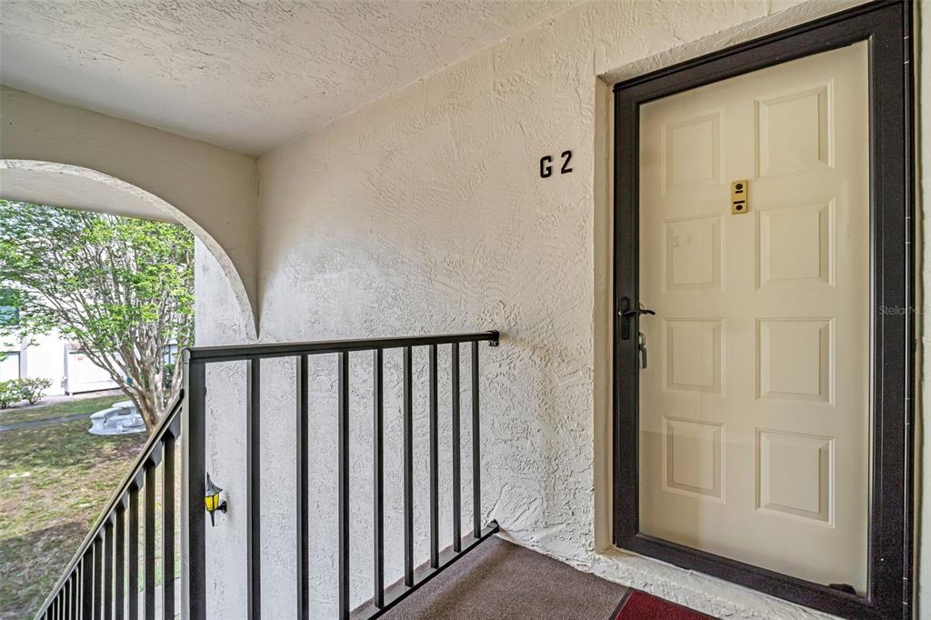 An exterior view of a building entrance with a white door labeled G2 — 2642 PINE RIDGE WAY S UNIT G2, PALM HARBOR, FL