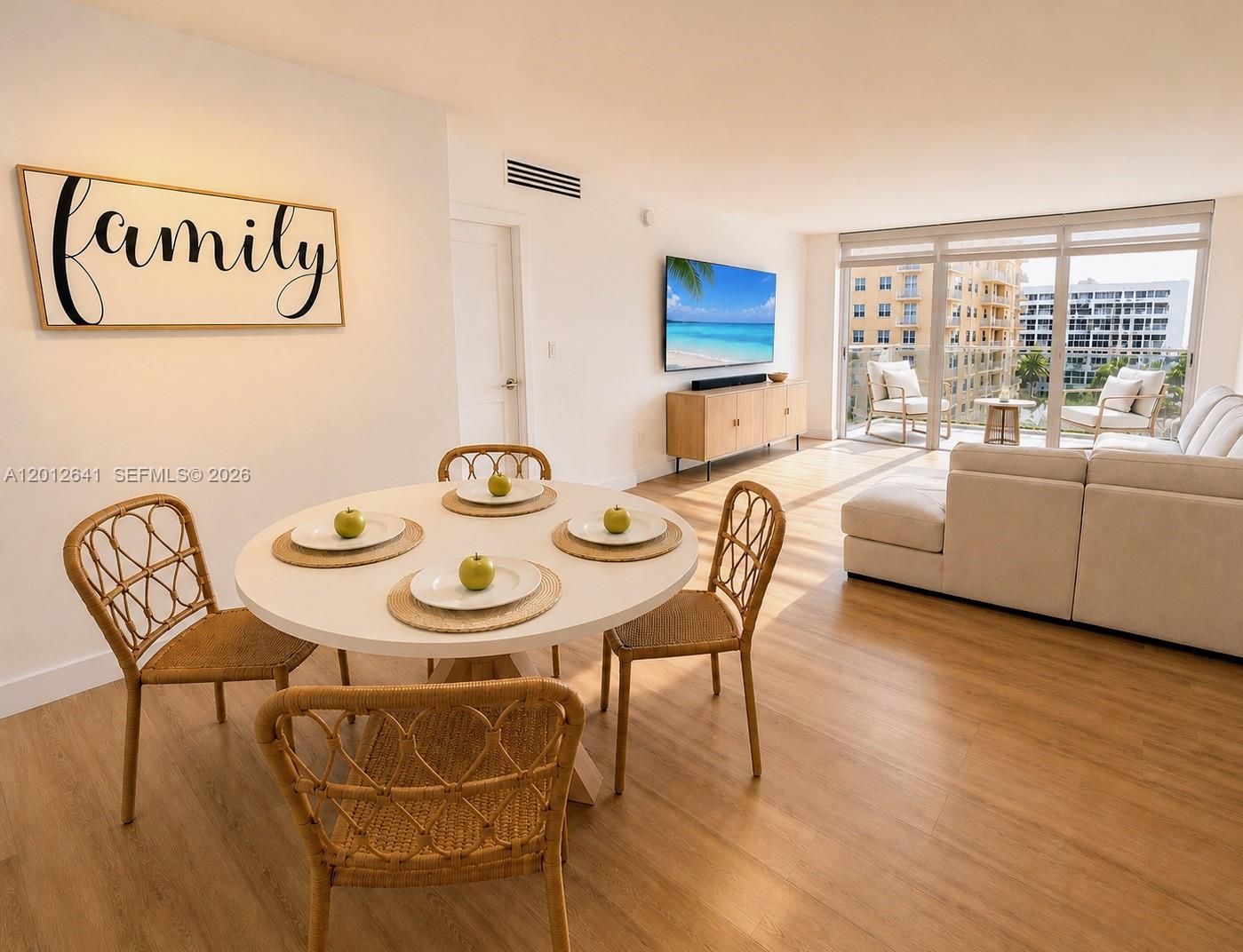 A bright dining and living area features a round table, wicker chairs, and balcony access — 2030 S Ocean Dr # 309, Hallandale Beach FL 33009, HALLANDALE BEACH, FL