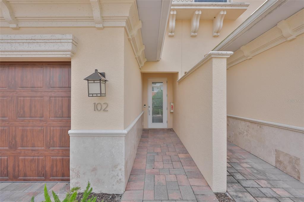 The exterior view shows a house entrance with a garage, stone accents, and a walkway — 7835 HIDDEN CREEK LOOP UNIT 102, BRADENTON, FL