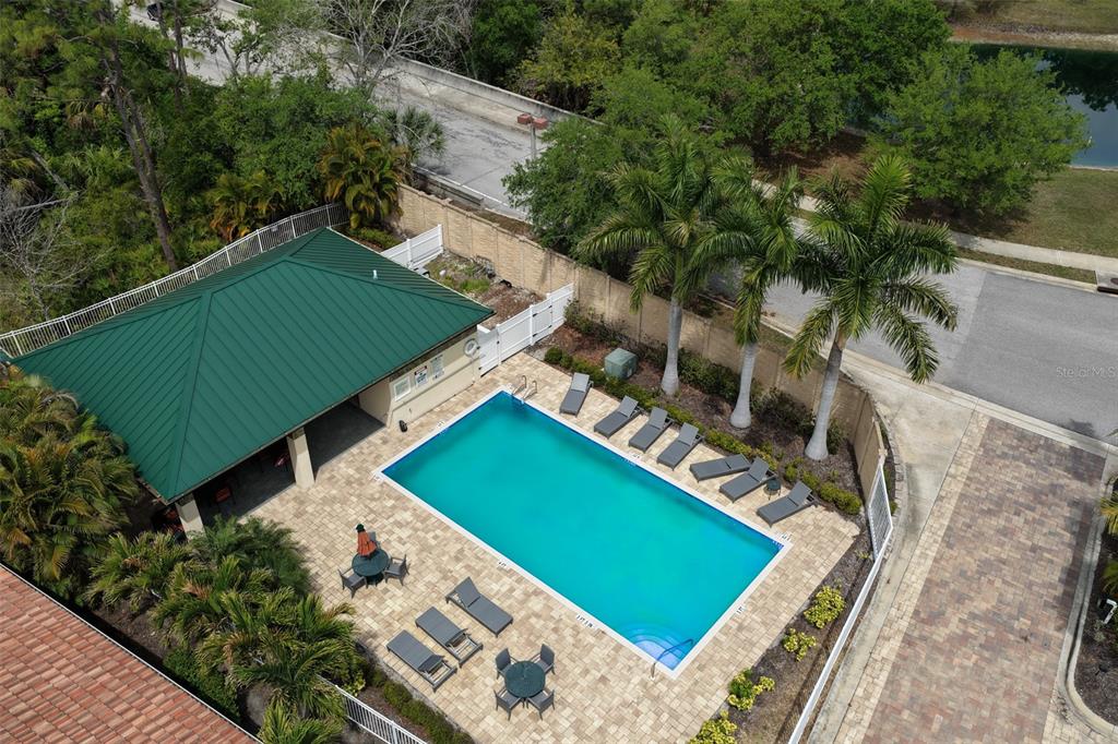 An aerial view shows a rectangular swimming pool with lounge chairs and a covered patio — 7835 HIDDEN CREEK LOOP UNIT 102, BRADENTON, FL