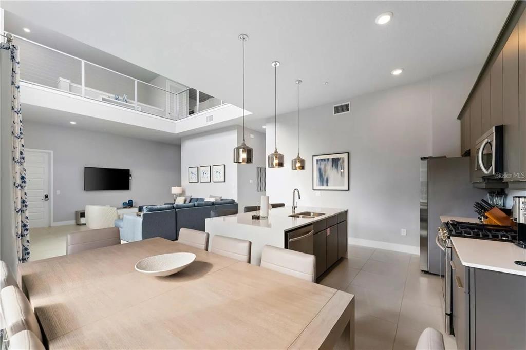 An open-concept kitchen and dining area features a large island, pendant lighting, and high ceilings — 7740 SANDY RIDGE DRIVE UNIT 211, REUNION, FL