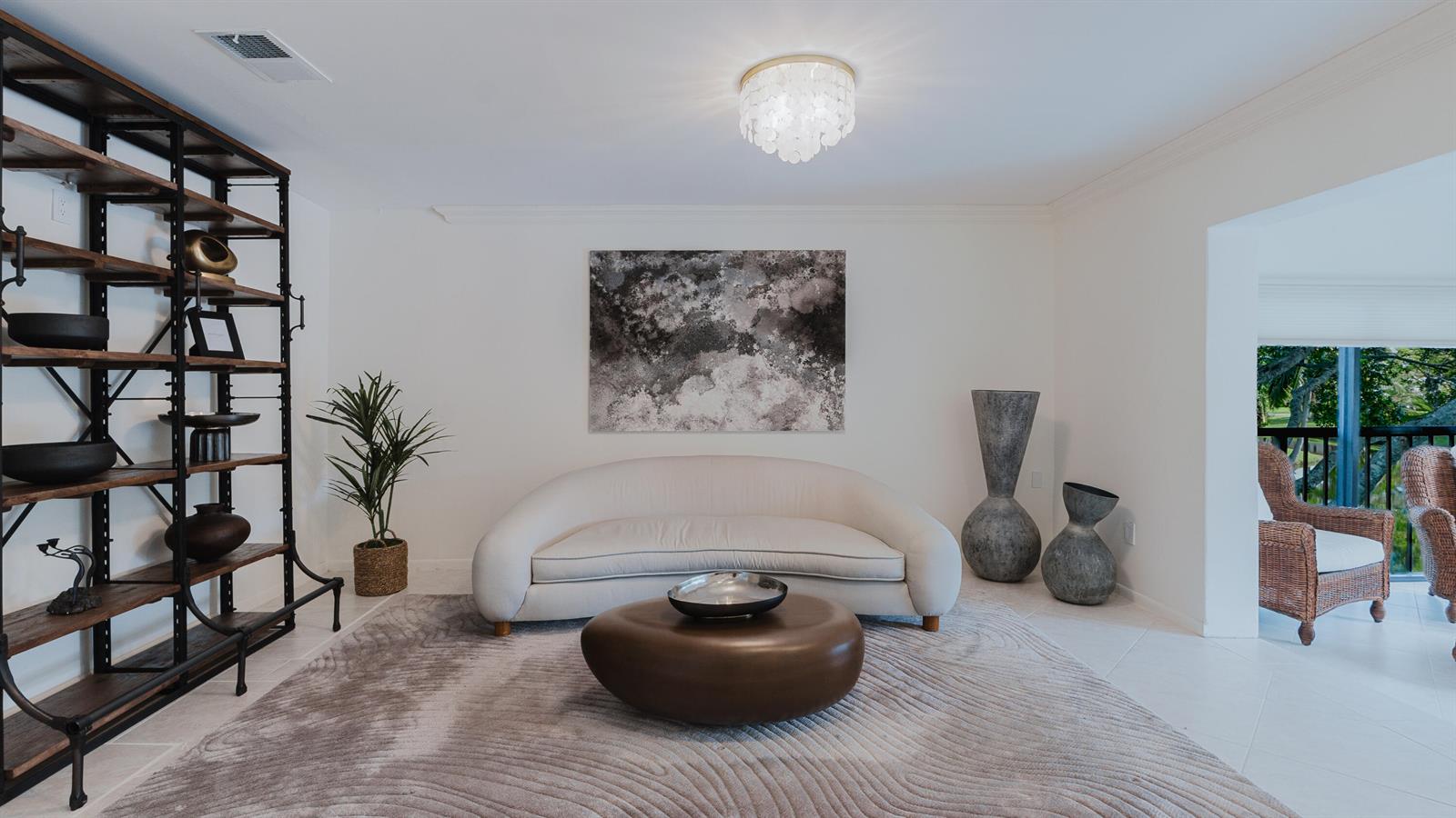 A living room features a curved white sofa, a round coffee table, and metal shelving — 9277 Vista Del Lago # B, Boca Raton FL 33428, BOCA RATON, FL