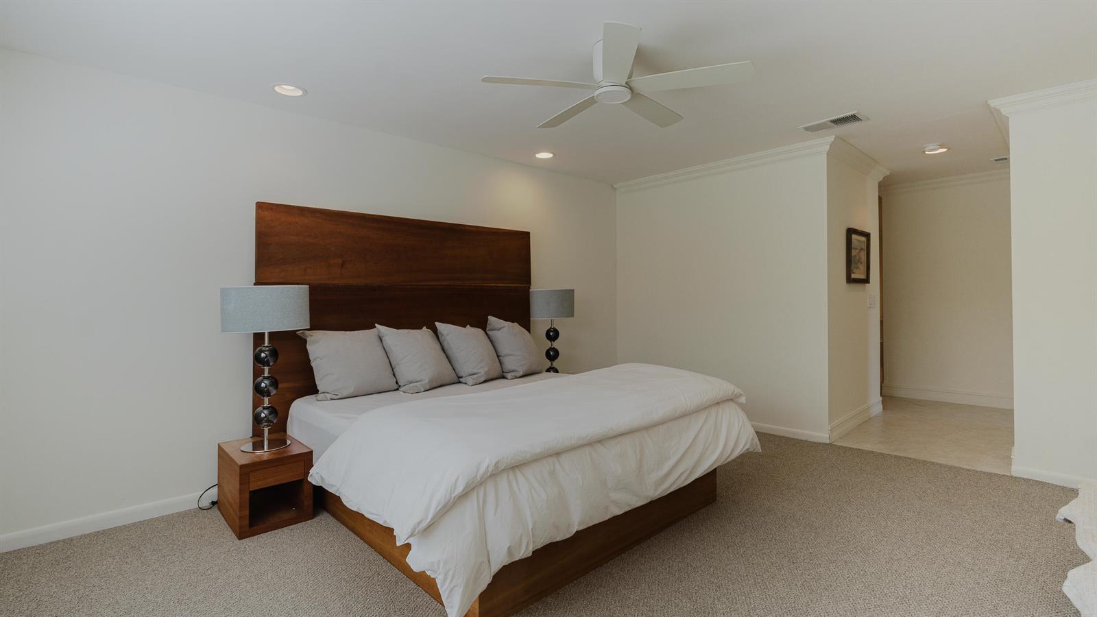 A bedroom features a wooden platform bed with a matching headboard and two bedside lamps — 9277 Vista Del Lago # B, Boca Raton FL 33428, BOCA RATON, FL