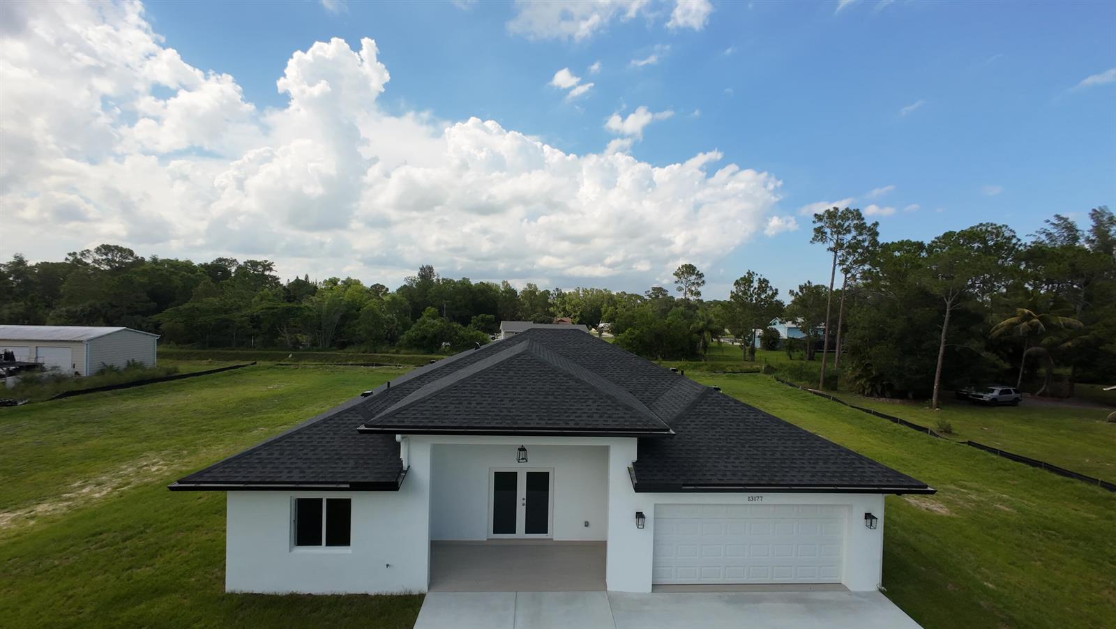 An aerial view of a single-story white house with a black roof and garage — 13177 47th Court N, FL 33411, FL