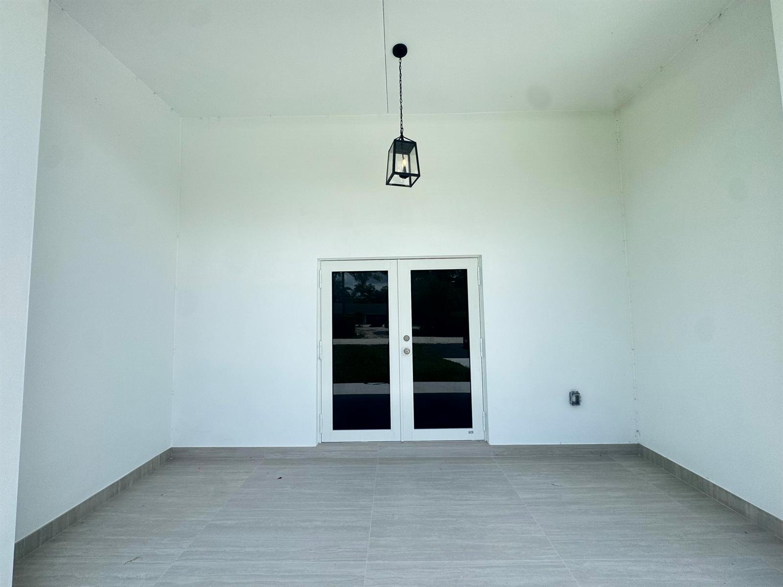 A covered patio features white walls, light-colored tile flooring, and a hanging lantern light fixture — 13177 47th Court N, FL 33411, FL