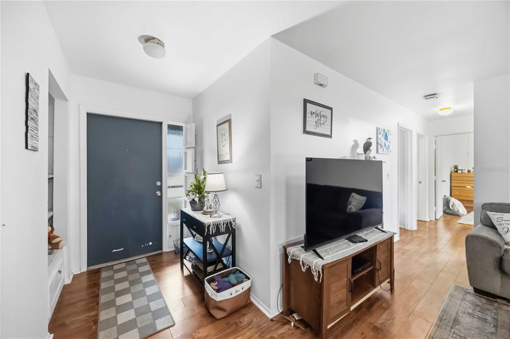 An entryway with a blue front door, wood flooring, and a television on a wooden stand — 5409 KENWOOD DRIVE, NORTH PORT, FL