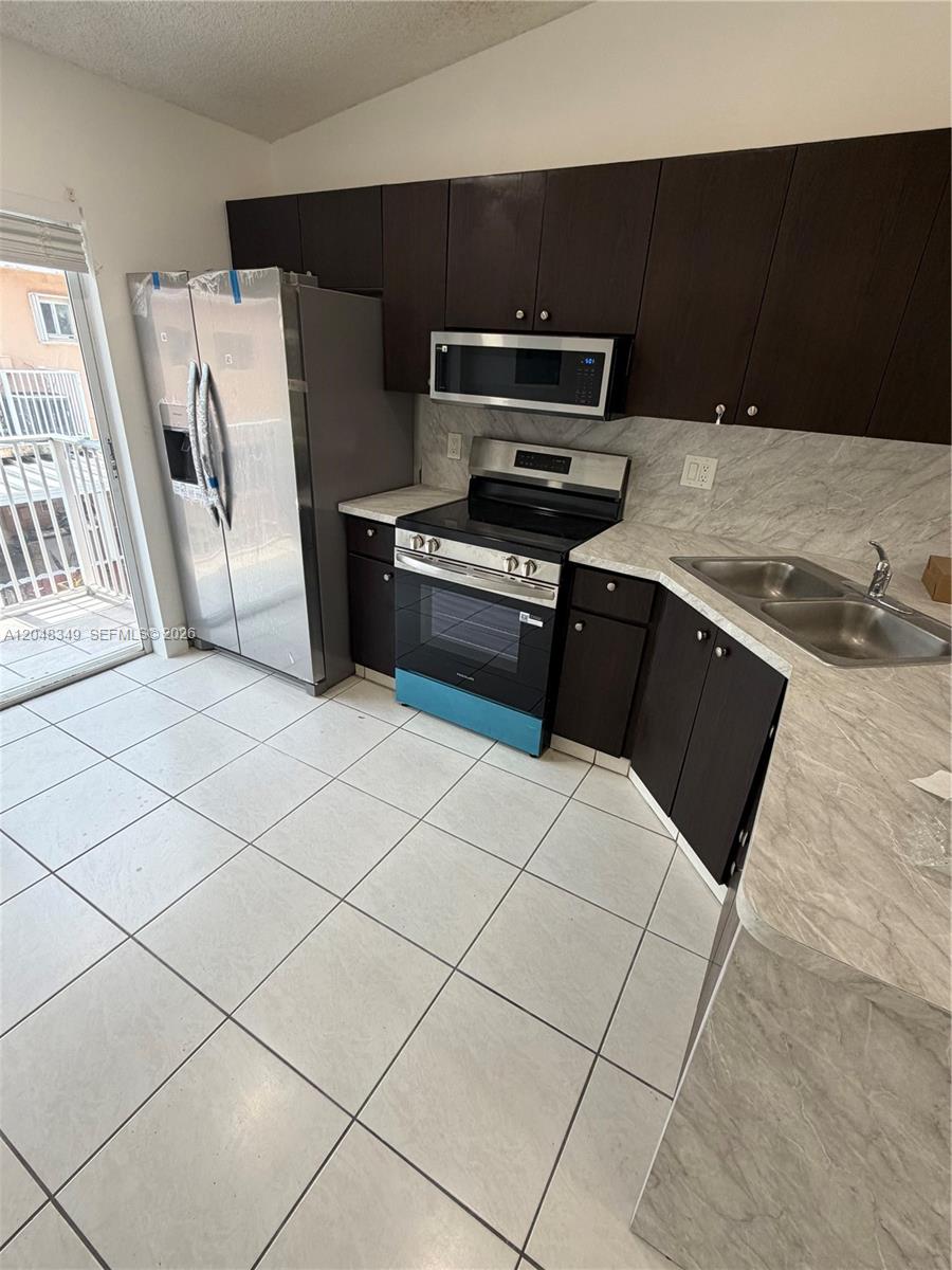 A two-story orange stucco building features a covered entryway and assigned parking spaces — 6823 W 36th Ave # 201, Hialeah FL 33018, HIALEAH, FL